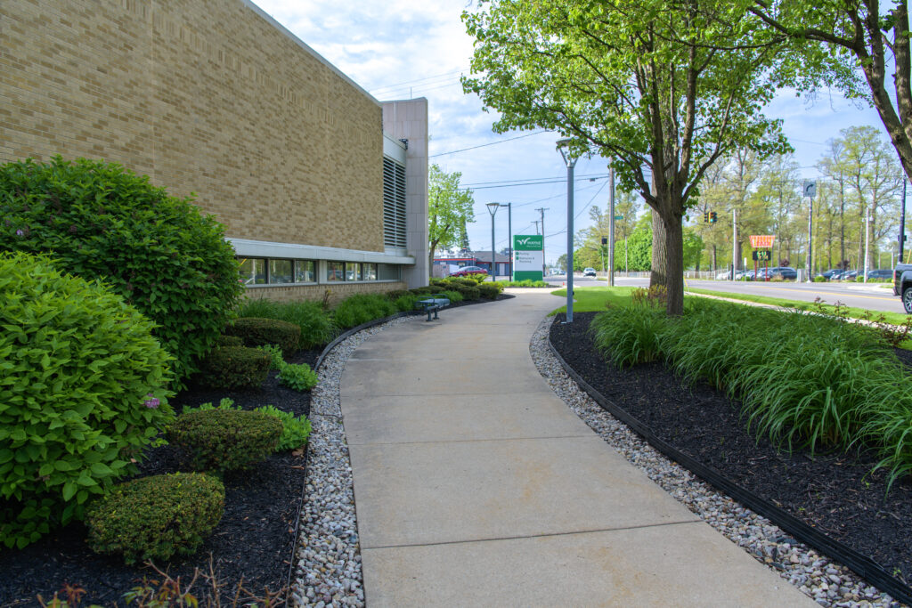 landscaped area of a commercial property, showing a paved path with river rock lining