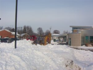commercial snow plow removing piles of snow burying a parking lot